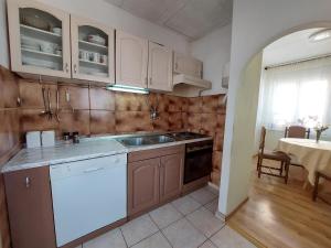 a kitchen with wooden cabinets and a sink and a table at Apartment KRUNO in Selce
