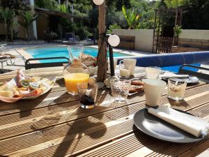 una mesa de madera con comida y bebidas junto a una piscina en La Villa Jasmin, en Montauroux