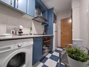 a kitchen with a washing machine and blue cabinets at Dos Torres Miraflores - Parking privado gratis in Zaragoza
