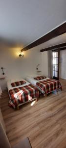 2 camas en una habitación con suelo de madera en Auberge du Gros Tilleul, en Argoules