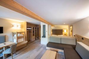 Habitación pequeña con cama, escritorio y mesa. en Design & Suite Hotel Ciarnadoi, en Vigo di Fassa