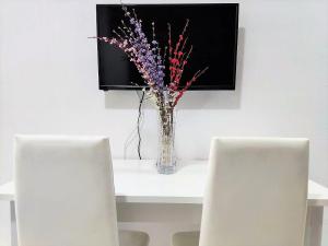 a vase of flowers on a table with two chairs at Apartamento Argentina, A/C, WIFI in Sanlúcar de Barrameda