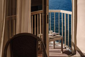 a table and a chair on a balcony with the ocean at The Diplomat Hotel in Sliema