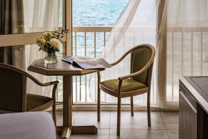 een tafel met twee stoelen en een vaas met bloemen bij The Diplomat Hotel in Sliema