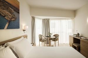 a hotel room with a bed and a table and chairs at The Diplomat Hotel in Sliema