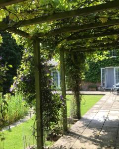 a wooden pergola in a garden with flowers at The Old Coach House at Stewton in Louth