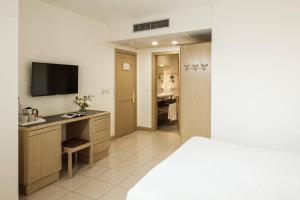 a bedroom with a desk with a television and a bathroom at The Diplomat Hotel in Sliema