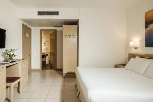 a hotel room with a white bed and a kitchen at The Diplomat Hotel in Sliema