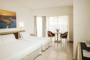 a hotel room with two beds and a table at The Diplomat Hotel in Sliema