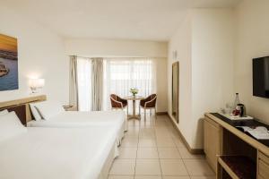 a hotel room with two beds and a table at The Diplomat Hotel in Sliema