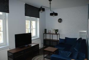 ein Wohnzimmer mit einem blauen Sofa und einem TV in der Unterkunft APARTAMENT CENTRUM OLSZTYNA 2 in Olsztyn