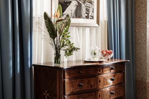 a wooden dresser with a vase of flowers on it at The Diplomat Hotel in Sliema