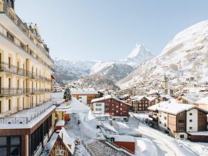 a town covered in snow with mountains in the background at BEAUSiTE Zermatt in Zermatt