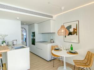 kuchnia z białymi szafkami i stołem z krzesłami w obiekcie AMAZING SEA VIEWS - The Wave, Brand new apartment w mieście Fuengirola