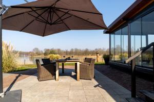 a patio with a table and chairs and an umbrella at Drents Genieten - Riegheide met privé jacuzzi in Erm