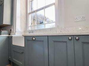 a kitchen with grey cabinets and a window at Windyridge in Settle