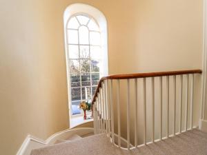 an arched window in a stairway with a dog looking out the door at Windyridge in Settle