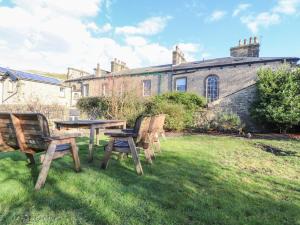 two benches and a table in the grass in front of a building at Windyridge in Settle