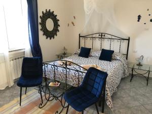 1 dormitorio con 1 cama con sillas azules y espejo en Zia Yaya, en Maratea