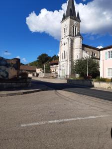 a church with a clock tower on a street at Gîte AUX 3 PTITS COCHONS in Cuisiat