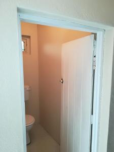 a bathroom with a toilet and a white door at Franskraal-Bit of Salt-Rustic Family Beach House-From R1650 per night, sleeps 6,min 2 nights in Franskraal +18 photos