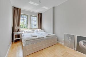 a white bedroom with a bed and a window at Grand Apartments - Lemon - Monte Cassino in Sopot