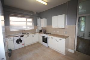 a kitchen with white cabinets and a washer and dryer at Harlesden Road Place in London