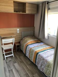 a bedroom with a bed and a desk and a chair at Mobil home neuf 6/8 pers in Biville-sur-Mer