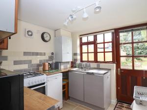 una cocina con electrodomésticos blancos y un reloj en la pared en Rose Cottage, en Ipswich