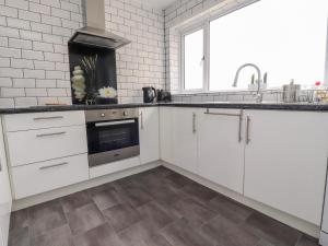 una cocina con armarios blancos y fregadero en The Beach House en Cleveleys