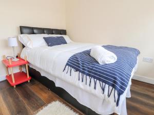 a bed with a blue and white blanket and a red table at The Beach House in Cleveleys