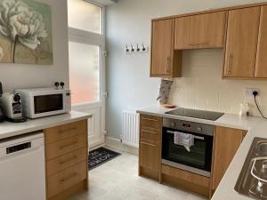 a kitchen with wooden cabinets and a microwave at Town House In The Heart of Pateley Bridge in Pateley Bridge