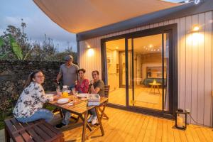 een groep mensen die aan een tafel op een patio zitten bij Azor'Oasis in Calhetas