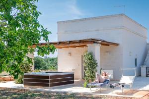 a woman sitting in a chair in front of a building at La Torretta Suite - Raro Rooms Collection in Ostuni