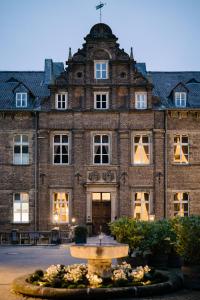 a large brick building with a fountain in front of it at Schlosshotel Hugenpoet in Essen