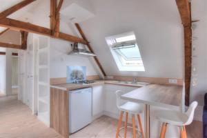 uma cozinha com armários brancos, uma mesa e bancos em Rêves Bleus - Côte de Granit Rose em Ploubezre