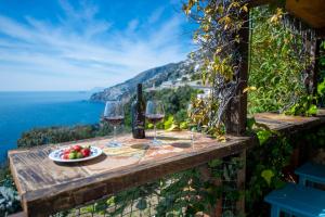 a table with two glasses of wine and a plate of fruit at Mareluna Cottage in Conca dei Marini +9 photos