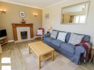 a living room with a blue couch and a fireplace at Ceris in Penrhyndeudreath