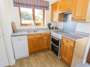 a kitchen with wooden cabinets and a white stove top oven at Ceris in Penrhyndeudreath