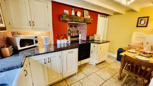 a kitchen with white cabinets and a microwave at Thornwell Cottage - Heart of the village, amazing gardens, glorious views and brimming with character in Dittisham +19 photos