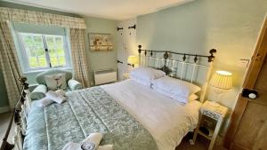 a bedroom with a large bed and a chair at Thornwell Cottage - Heart of the village, amazing gardens, glorious views and brimming with character in Dittisham