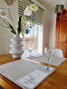 un tavolo con due bicchieri da vino e un vaso con fiori di ''Op Stok" a Bergen