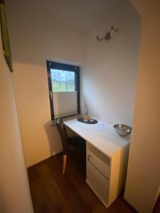 einen Schreibtisch in einem Zimmer mit einem Fenster und einem Schreibtisch mit einem Stuhl in der Unterkunft Pension Wittgensteiner Schweiz in Bad Berleburg