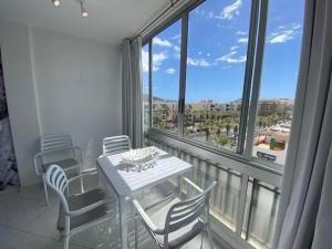 een tafel en stoelen in een kamer met een groot raam bij EL DORADO HOLIDAYS in Playa de las Americas