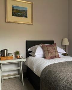 a bedroom with a bed and a table with a night stand at Ardvreck House in Ullapool