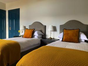 two beds with orange pillows in a hotel room at Ardvreck House in Ullapool