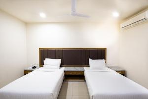 two beds in a room with white sheets at Agrasen Foundation Managed by TGB foods Pvt Ltd in Ahmedabad