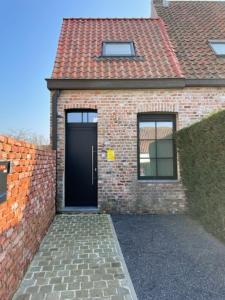 una casa in mattoni con una porta nera e due finestre di Gezellige vakantiewoning nabij Damme a Damme