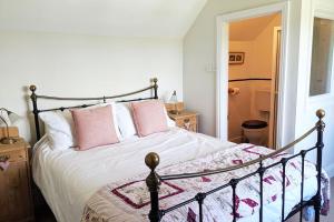 a bedroom with a large bed with pink pillows at 1 Rock Cottage - Beautifully Presented Cottage for Four with Wood Burner in Dittisham