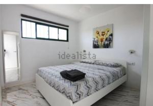 Un dormitorio blanco con una cama con una bolsa negra. en Casita Paraiso 255 en Costa de Antigua